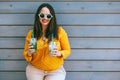 Plus size woman drinking take away cocktail over city cafe wall Royalty Free Stock Photo