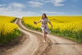 Plus size woman in floral dress, barefoot, on a road between canola fields Royalty Free Stock Photo