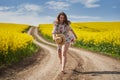 Plus size woman in floral dress, barefoot, on a road between canola fields Royalty Free Stock Photo