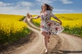 Plus size woman in floral dress, barefoot, on a road between canola fields Royalty Free Stock Photo