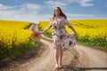Plus size woman in floral dress, barefoot, on a road between canola fields Royalty Free Stock Photo