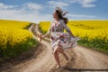 Plus size woman in floral dress, barefoot, on a road between canola fields Royalty Free Stock Photo