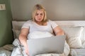 Plus-size woman focused on laptop, engaged in work or browsing online from bed Royalty Free Stock Photo