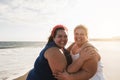 Plus size women friends having fun on the beach with sunset in background - Soft focus on left female face Royalty Free Stock Photo