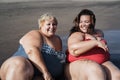 Plus size women sitting on the beach having fun during summer vacation - Focus on right girl face Royalty Free Stock Photo