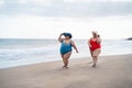 Plus size women walking on the beach having fun during summer vacation - Curvy female laughing together - Overweight body and