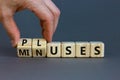 Pluses and minuses symbol. Businessman turns wooden cubes and changes the word `minuses` to `pluses`. Beautiful grey table, gr Royalty Free Stock Photo