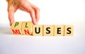 Pluses and minuses symbol. Businessman turns wooden cubes and changes the word `minuses` to `pluses`. Beautiful white table, w Royalty Free Stock Photo