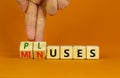 Pluses and minuses symbol. Businessman turns wooden cubes and changes the word `minuses` to `pluses`. Beautiful orange table, Royalty Free Stock Photo