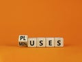 Pluses and minuses symbol. Turned a wooden cube and changed the word `minuses` to `pluses`. Beautiful orange table, orange Royalty Free Stock Photo