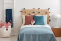 Plush fox on singe bed with colorful pillows and duvet