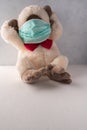 Plush monkey in medical mask put her head in paws on the light background with space for copying