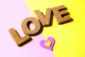 A plush pink and yellow heart shape on a matching background with cork letters spelling the word love. Harsh lighting and hard Royalty Free Stock Photo