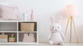 Plush rabbit white bedside cabinet next to cupboard, lamp pink DIY bags in child room. generative ai