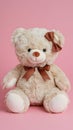Plush teddy bear with bow evokes warmth and comfort on pink background Royalty Free Stock Photo