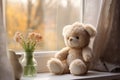 Plush teddy bear with flowers on sunny window sill