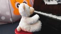 A plush, white, furry bear sits on a red chair and plays a baby