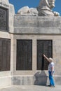 Plymouth Navy Memorial with an elderly lady reaching up and touching a list of names