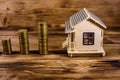 Plywood model of the house and stacks of coins on wooden background Royalty Free Stock Photo