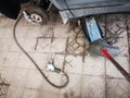 Pneumatic wrench with car tire nuts on the concrete floor aside car jack lift and a piece of rusted metal to fix car tire