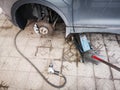 Pneumatic wrench with car tire nuts on the concrete floor aside car jack lift and a piece of rusted metal to fix car tire
