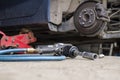 Pneumatic wrench tool on the asphalt and a car jack for lift up the body and changing the tire. Car without wheel Royalty Free Stock Photo