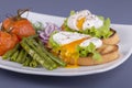 Poached egg on a piece of bread with fried green beans, tomato and arugula on a plate Royalty Free Stock Photo