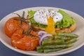 Poached egg on a piece of bread with fried green beans, tomato and arugula on a plate Royalty Free Stock Photo