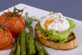 Poached egg on a piece of bread with fried green beans, tomato and arugula on a plate Royalty Free Stock Photo