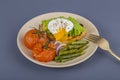 Poached egg on a piece of bread with fried green beans, tomato and arugula on a plate Royalty Free Stock Photo