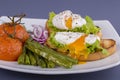 Poached egg on a piece of bread with fried green beans, tomato and arugula on a plate Royalty Free Stock Photo