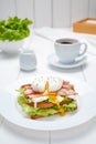 Poached egg sandwich with bacon, salad, mayonnaise, tomatoes, toasted bread