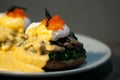 Poached egg with spinach, mushrooms topping with red caviar on burger. Wooden cutting board