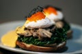 Poached egg with spinach, mushrooms topping with red caviar on burger. Wooden cutting board