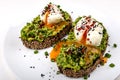 Poached eggs with avocado guacomole on brown bread with sesame seeds. Healthy breakfast on a white background. Royalty Free Stock Photo