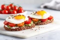 poached eggs on avocado toast with cherry tomatoes on a marble slab Royalty Free Stock Photo