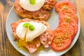 Poached eggs served on toast with bacon and tomato and herbs Royalty Free Stock Photo