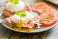 Poached eggs served on toast with bacon and tomato and herbs Royalty Free Stock Photo