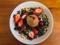 Poached pear and fresh berries granola breakfast cereal served in white bowl set on wooden table Royalty Free Stock Photo