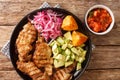 Poc chuc is a Mexican meat dish consisting of thin pork cutlets marinated in orange juice closeup in the plate. Horizontal top