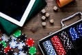 Pocker set in a metallic case nearby tablet on a wooden table top view