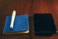 Pocket book, pen and mobile smart phone on table Royalty Free Stock Photo