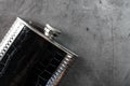 Pocket flask in leather finish with a drink on a dark background with copy space Royalty Free Stock Photo