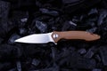 Pocket folding knife with a brown handle. Shiny knife on the corner. Color and contrast