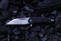 Pocket knife lying on cold coals. Top view of a knife and coal