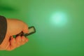 Pocket led flashlight in hand. illuminates green background. Copy space Royalty Free Stock Photo