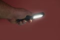 Pocket led flashlight in hand. illuminates red background. Copy space Royalty Free Stock Photo