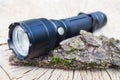 Pocket LED flashlight lies on a tree bark Royalty Free Stock Photo