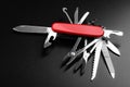 Pocket red Swiss knife packed with accessories fully opened on black matte background. Royalty Free Stock Photo