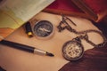 Pocket watch with old books and pen with paper map on the table. Royalty Free Stock Photo